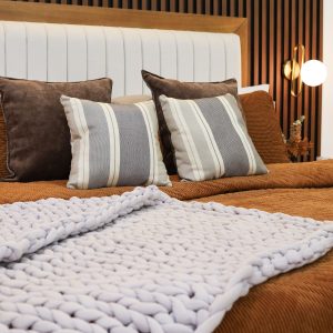 Elegant modern bedroom featuring striped pillows and a woven blanket.